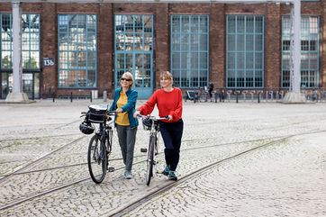 Radfahrerinnen erkunden auf der Radroute „Warmes Licht und kühles Bier“ die AEG am Humboldthain in Berlin. Foto: Thomas Kierok